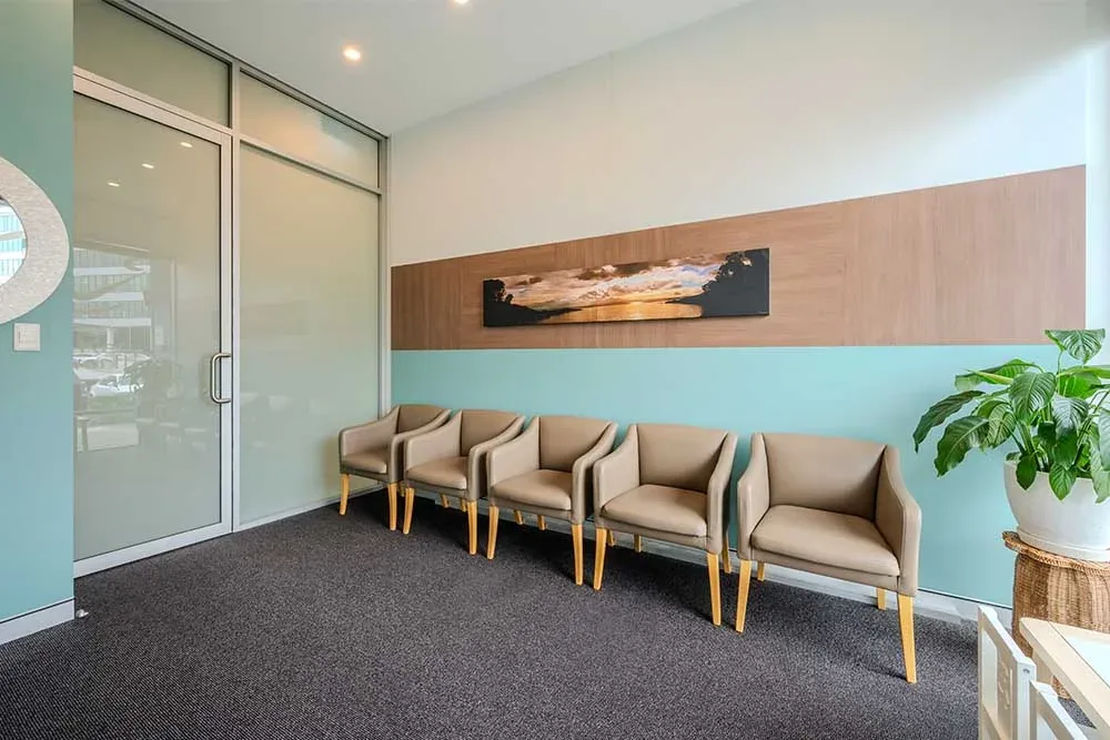 Waiting room with teal feature wall and tan armchairs at Beyond Smiles Family Dental